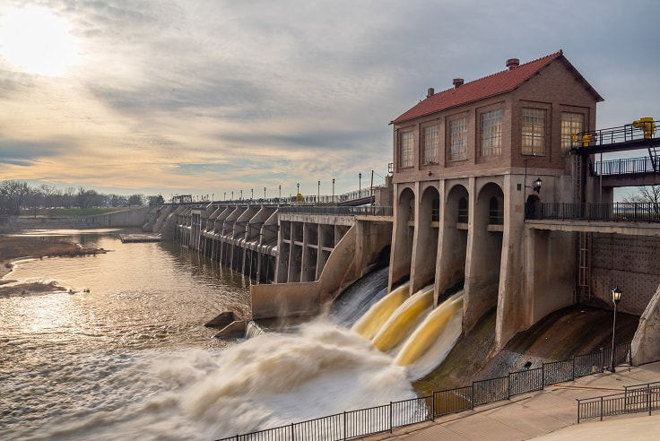 Late afternoon photo of dam with water flowing out of the gates