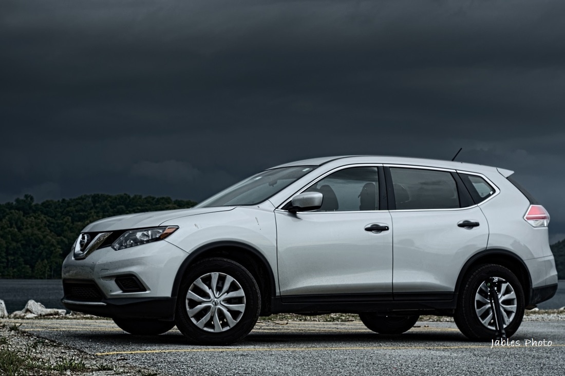 2016 Nissan Rogue parked near Beaver Lake dam with storm in background